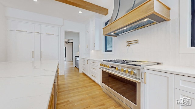 kitchen featuring stainless steel stove, white cabinets, custom exhaust hood, light stone countertops, and beam ceiling