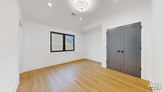 unfurnished bedroom featuring lofted ceiling, hardwood / wood-style floors, and a closet