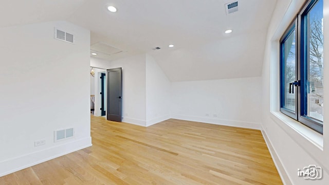 additional living space featuring vaulted ceiling and light hardwood / wood-style floors