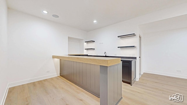 kitchen with sink, light wood-type flooring, and kitchen peninsula