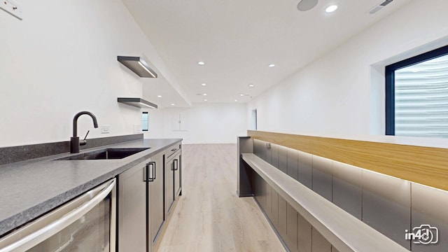 kitchen with sink, dishwasher, and light wood-type flooring