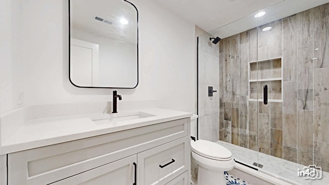 bathroom with walk in shower, vanity, and toilet