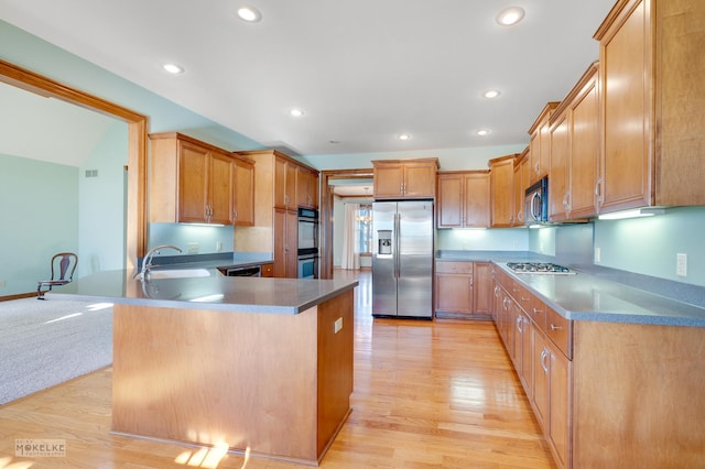 kitchen featuring appliances with stainless steel finishes, sink, light hardwood / wood-style floors, and kitchen peninsula