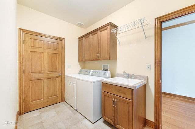 laundry area with cabinets, independent washer and dryer, and sink