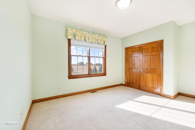 unfurnished bedroom featuring light colored carpet and a closet