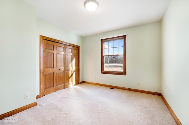 unfurnished bedroom with light carpet and a closet