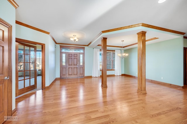 foyer entrance featuring decorative columns, crown molding, an inviting chandelier, and light hardwood / wood-style flooring