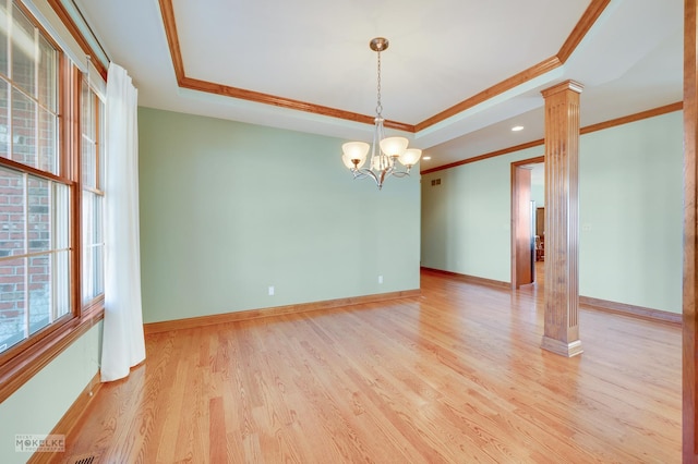 unfurnished room with crown molding, a tray ceiling, light wood-type flooring, and ornate columns