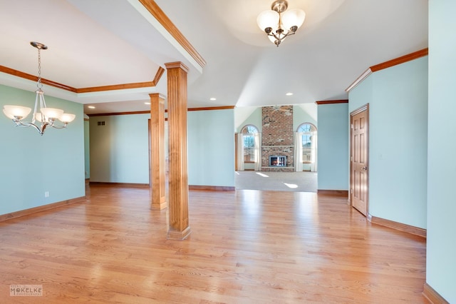 unfurnished living room with ornate columns, an inviting chandelier, and light hardwood / wood-style flooring