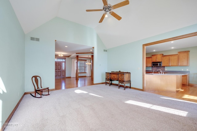 living room with high vaulted ceiling, light colored carpet, sink, and ceiling fan