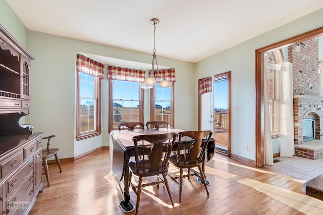 dining area featuring a brick fireplace and light wood-type flooring