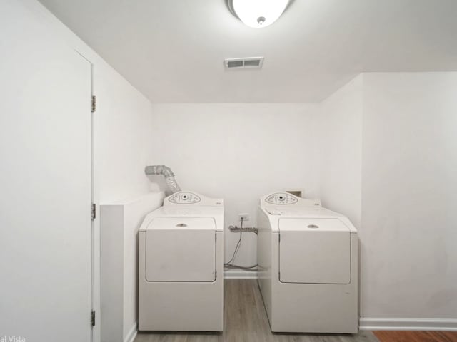 laundry room with separate washer and dryer and light wood-type flooring