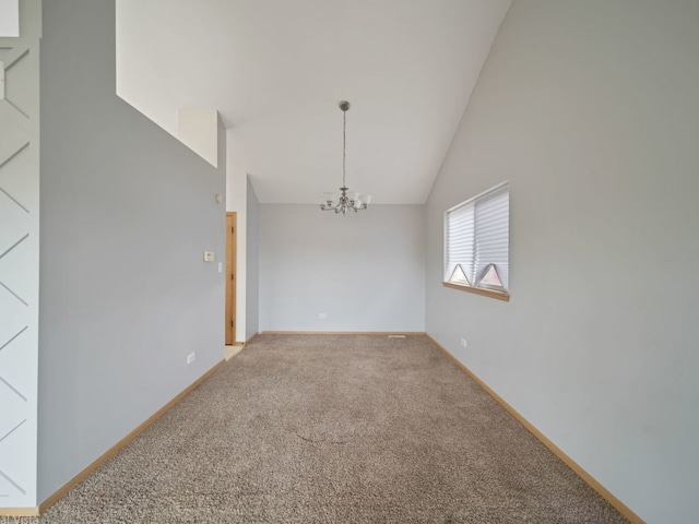 carpeted spare room featuring vaulted ceiling and a notable chandelier