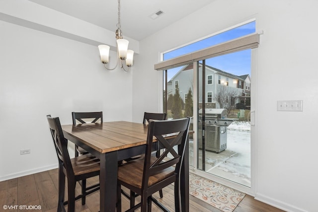 dining space featuring dark hardwood / wood-style flooring and a chandelier