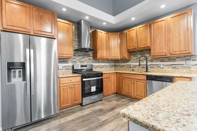 kitchen featuring sink, wall chimney range hood, hardwood / wood-style flooring, stainless steel appliances, and backsplash