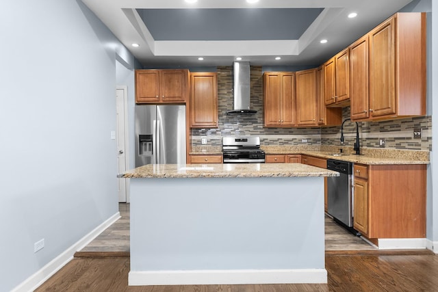 kitchen featuring light stone countertops, a kitchen island, wall chimney range hood, and appliances with stainless steel finishes