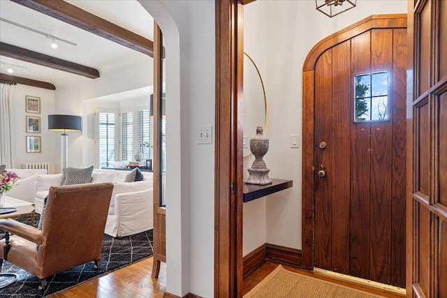 entryway featuring beam ceiling, radiator heating unit, and light hardwood / wood-style floors