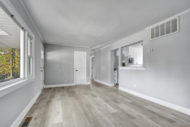 unfurnished living room with ornamental molding and light hardwood / wood-style floors