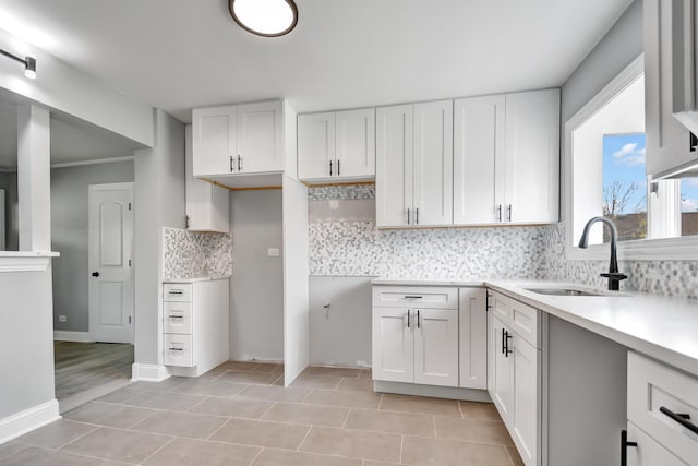 kitchen featuring white cabinetry, sink, backsplash, and light tile patterned flooring