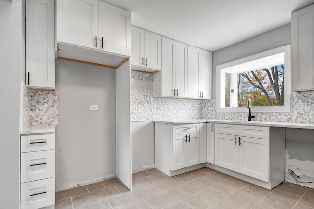 kitchen featuring light tile patterned floors, decorative backsplash, and white cabinets