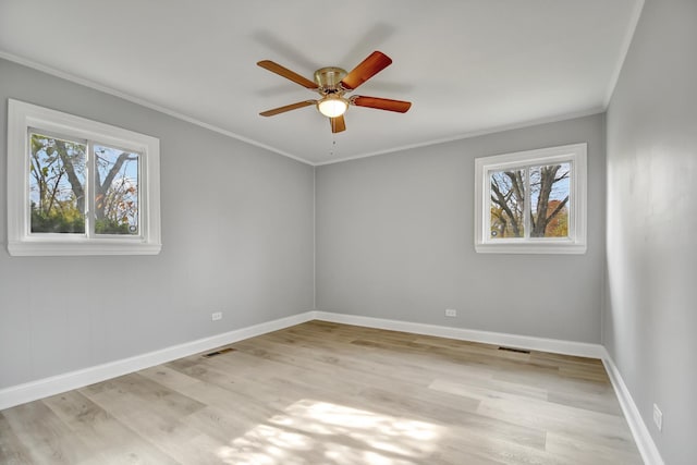 empty room featuring plenty of natural light, ornamental molding, ceiling fan, and light wood-type flooring