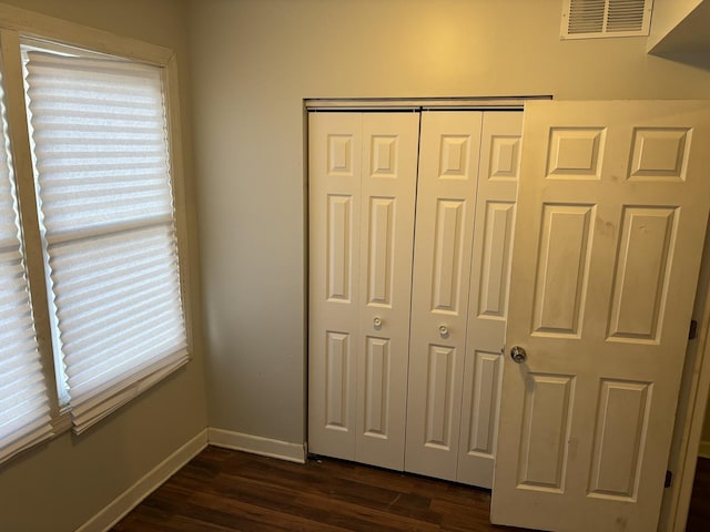 unfurnished bedroom with dark hardwood / wood-style floors and a closet