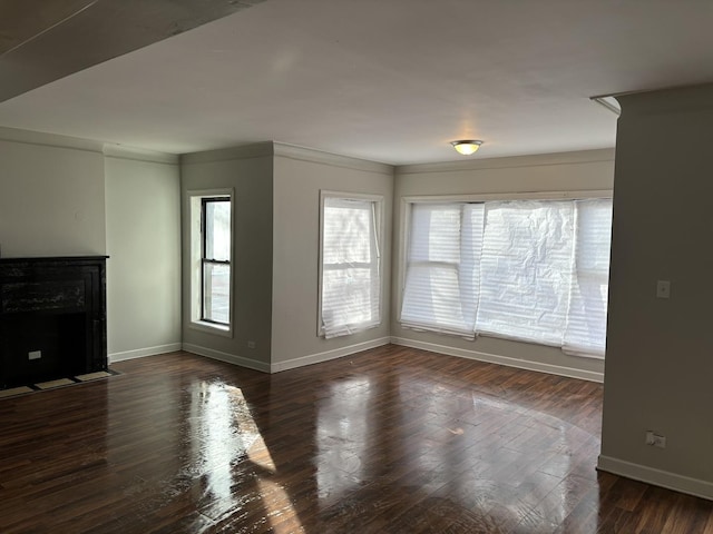 unfurnished living room with dark hardwood / wood-style flooring, crown molding, and a wealth of natural light