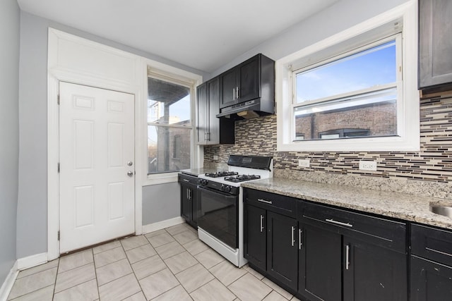 kitchen with white range with gas cooktop, backsplash, light stone counters, and light tile patterned floors