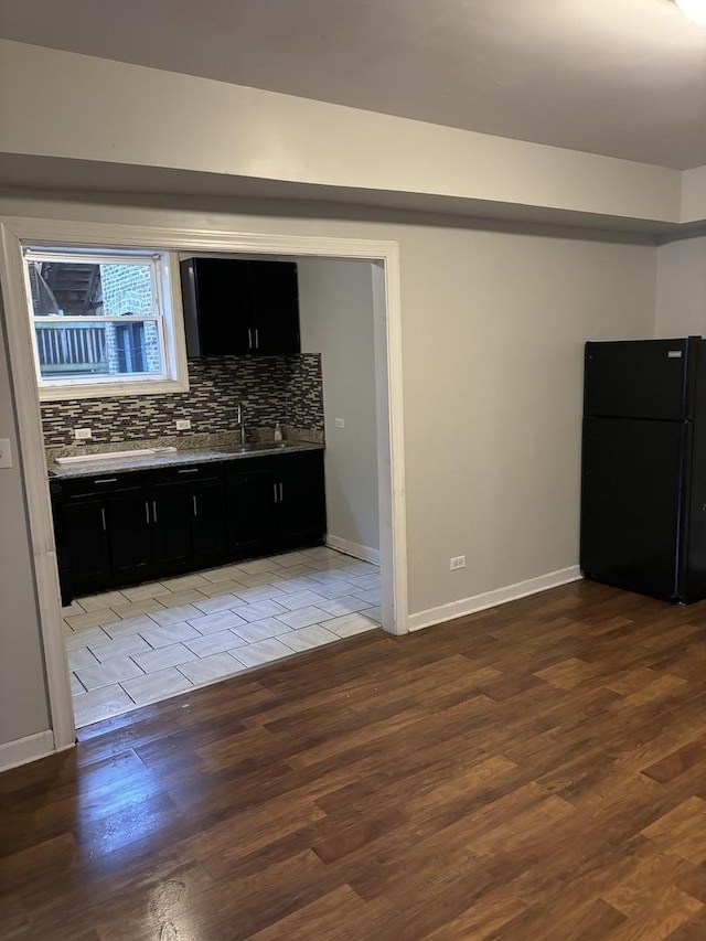 kitchen featuring black fridge, sink, decorative backsplash, and light hardwood / wood-style flooring