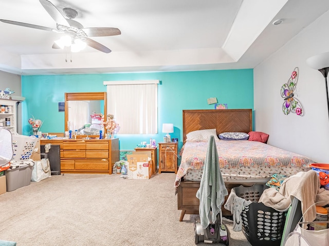 bedroom featuring a raised ceiling, carpet floors, and ceiling fan