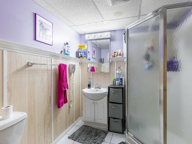 bathroom with tile patterned flooring, an enclosed shower, a drop ceiling, toilet, and wood walls