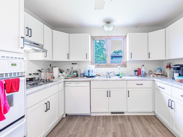 kitchen featuring white cabinetry, white appliances, light hardwood / wood-style floors, and sink