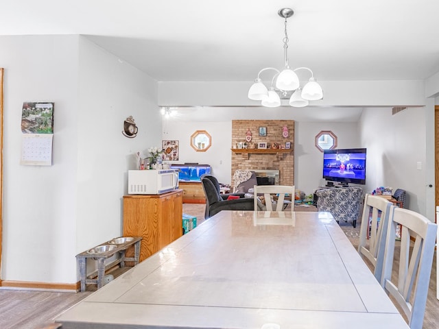 dining space featuring an inviting chandelier, a fireplace, and light wood-type flooring