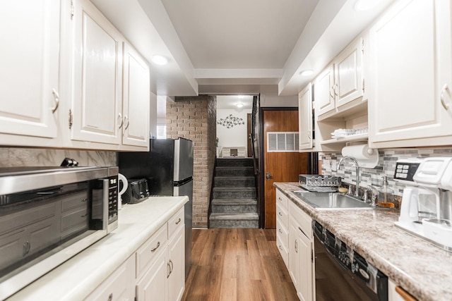 kitchen with appliances with stainless steel finishes, sink, backsplash, white cabinetry, and dark hardwood / wood-style floors