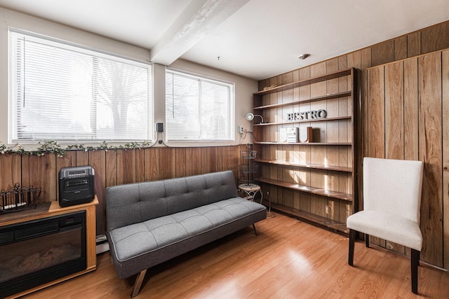 sitting room with light hardwood / wood-style floors, wooden walls, and beam ceiling