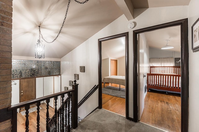 hallway with hardwood / wood-style floors, a notable chandelier, and lofted ceiling with beams