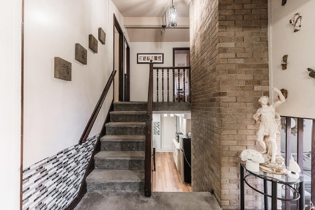 stairs featuring hardwood / wood-style flooring and brick wall