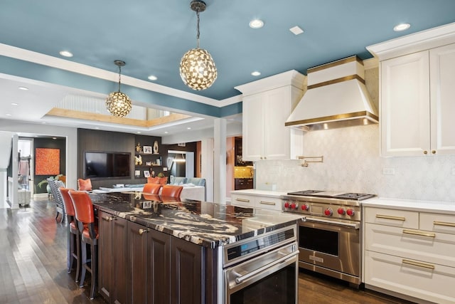 kitchen with a kitchen bar, custom exhaust hood, white cabinetry, stainless steel appliances, and backsplash