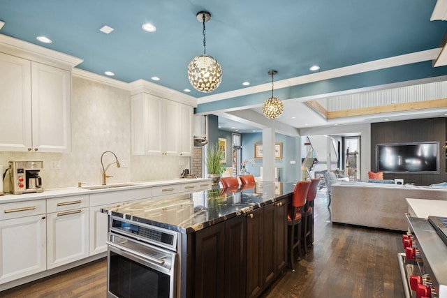 kitchen with white cabinetry, sink, decorative backsplash, and stainless steel oven