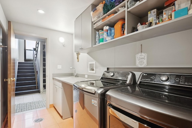 washroom featuring cabinets, sink, light tile patterned floors, and washer and clothes dryer