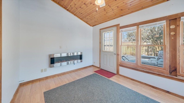 entryway with vaulted ceiling, wooden ceiling, a fireplace, and light wood finished floors