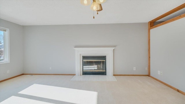 unfurnished living room with a fireplace with flush hearth, light carpet, ceiling fan, a textured ceiling, and baseboards