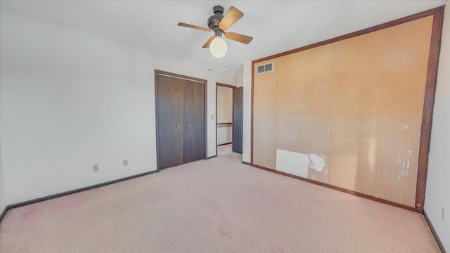 unfurnished bedroom featuring ceiling fan, light colored carpet, visible vents, baseboards, and a closet