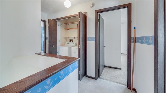 corridor featuring light carpet, separate washer and dryer, and a textured ceiling