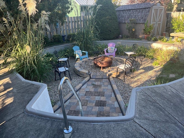 view of patio / terrace with an outbuilding, fence, a fire pit, and a shed