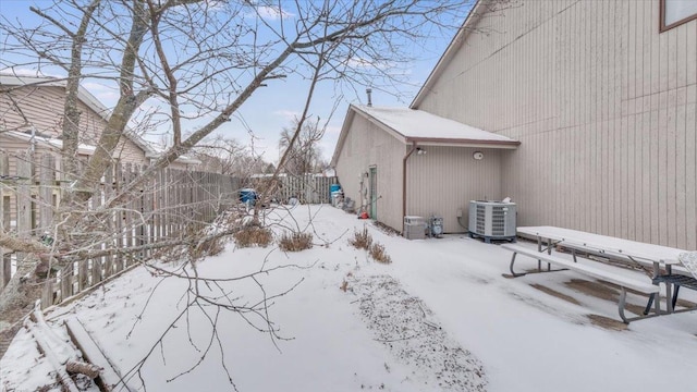 yard layered in snow with fence and central AC unit