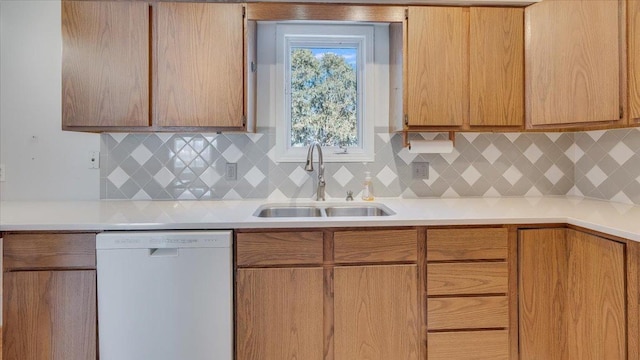 kitchen featuring dishwasher, light countertops, a sink, and decorative backsplash