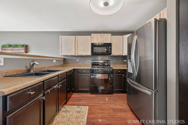 kitchen with dark brown cabinetry, sink, light hardwood / wood-style floors, decorative backsplash, and black appliances