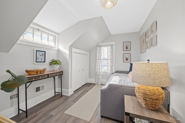 bedroom with dark wood-type flooring, lofted ceiling, and a closet