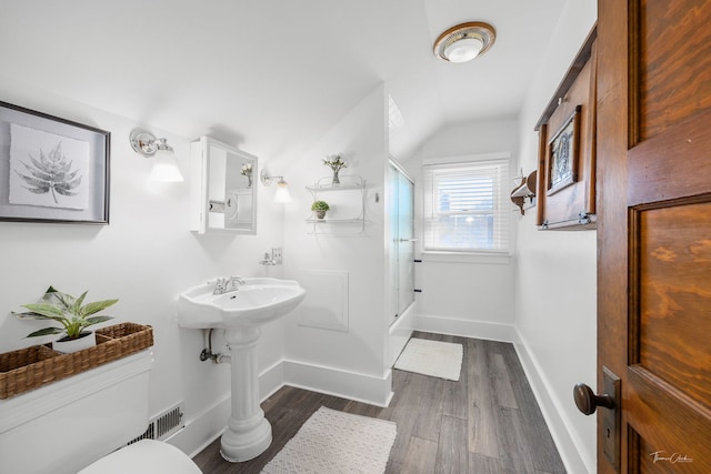 bathroom with lofted ceiling, hardwood / wood-style flooring, a shower with shower door, and toilet